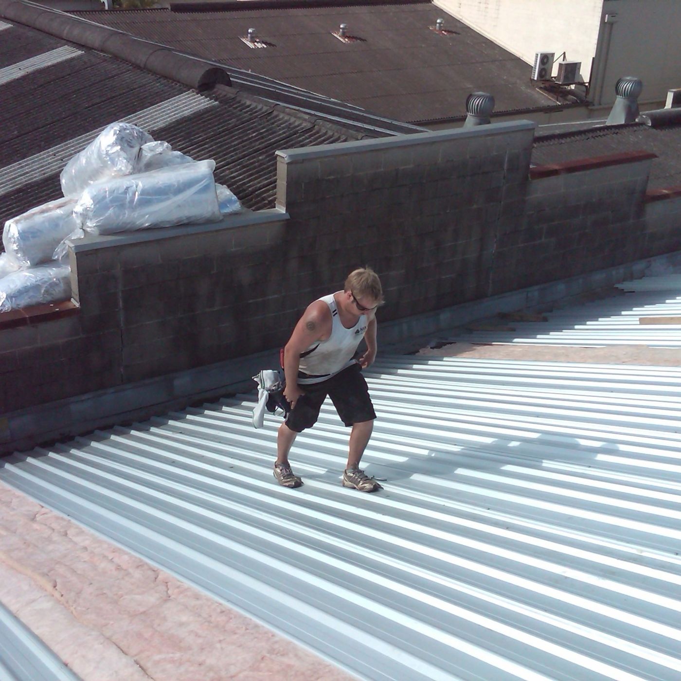 VIP Roofing crew member laying new metal roof sheeting on a commercial building